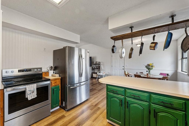 kitchen with green cabinetry, light countertops, appliances with stainless steel finishes, a textured ceiling, and light wood-type flooring