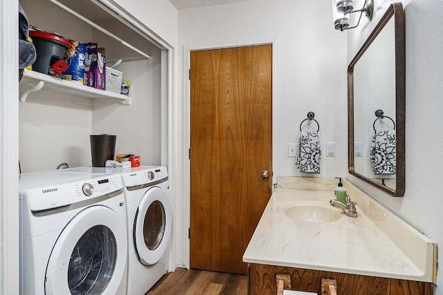 laundry room with washing machine and clothes dryer, laundry area, wood finished floors, and a sink