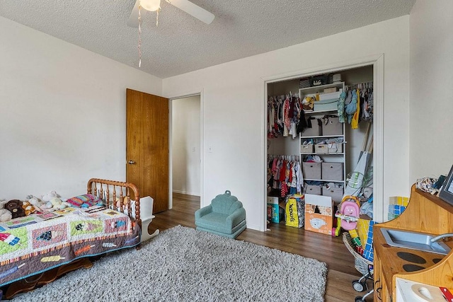 bedroom with a closet, a textured ceiling, wood finished floors, and a ceiling fan