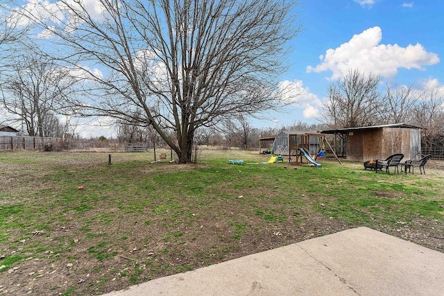 view of yard with a playground, an outdoor structure, and fence