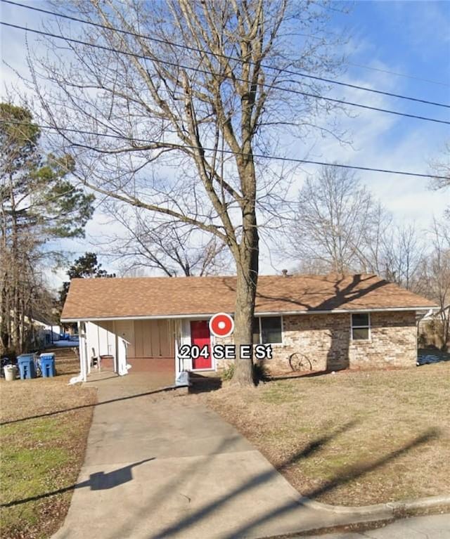 view of front facade featuring driveway, a front lawn, and roof with shingles