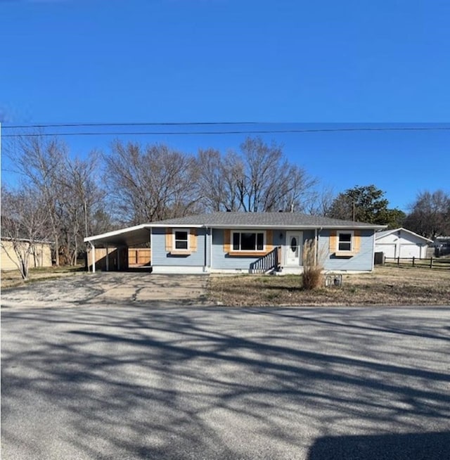 view of front facade featuring a carport, fence, and driveway