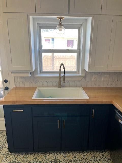 kitchen featuring decorative backsplash, white cabinets, blue cabinetry, and a sink