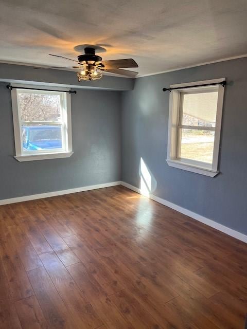 spare room with a wealth of natural light, a ceiling fan, baseboards, and wood finished floors