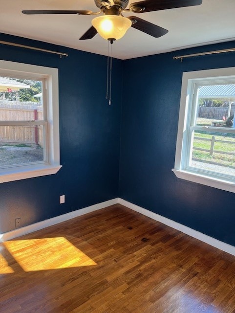 unfurnished room with a wealth of natural light, a ceiling fan, baseboards, and wood finished floors