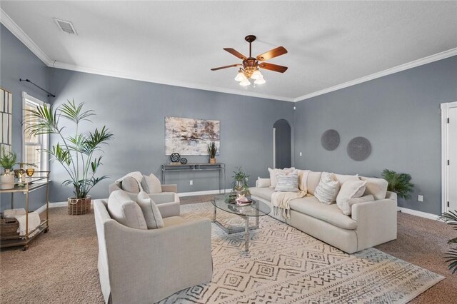 carpeted living area featuring visible vents, arched walkways, baseboards, and crown molding