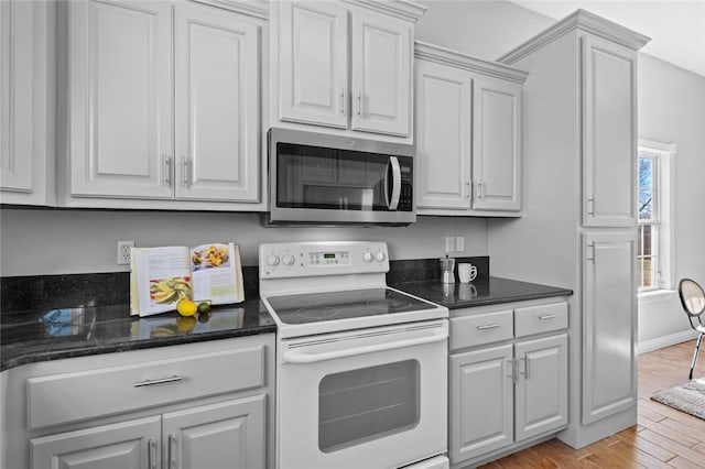 kitchen featuring stainless steel microwave, light wood finished floors, baseboards, and electric stove