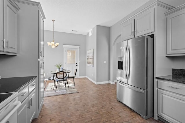 kitchen featuring dark countertops, range with electric cooktop, stainless steel fridge with ice dispenser, an inviting chandelier, and wood finished floors