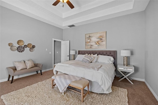 carpeted bedroom featuring visible vents, a raised ceiling, baseboards, and ceiling fan