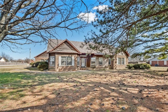 view of front facade with a front yard, fence, and brick siding