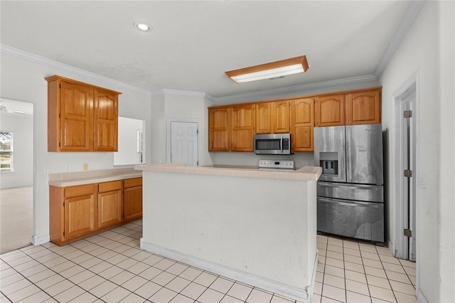 kitchen featuring tile countertops, a kitchen island, light tile patterned flooring, stainless steel appliances, and crown molding