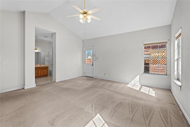 interior space featuring light colored carpet, baseboards, a ceiling fan, and vaulted ceiling