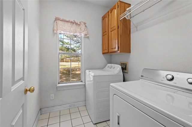 washroom featuring a wealth of natural light, cabinet space, separate washer and dryer, and light tile patterned floors