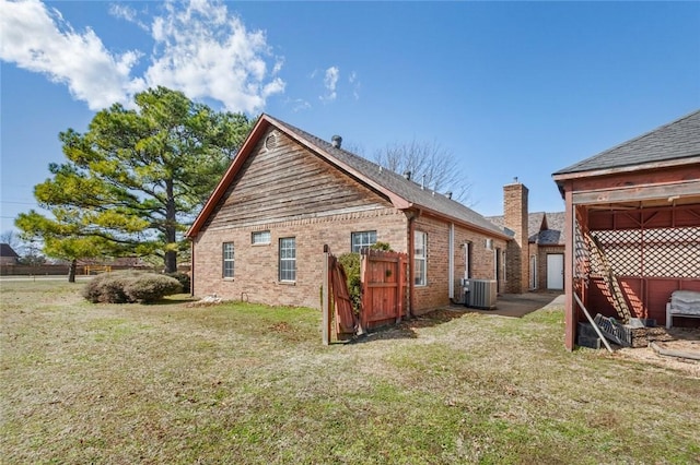 view of property exterior featuring brick siding, a lawn, cooling unit, and fence