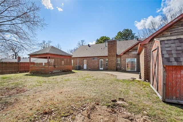 back of house with brick siding, fence, a gazebo, a chimney, and a patio