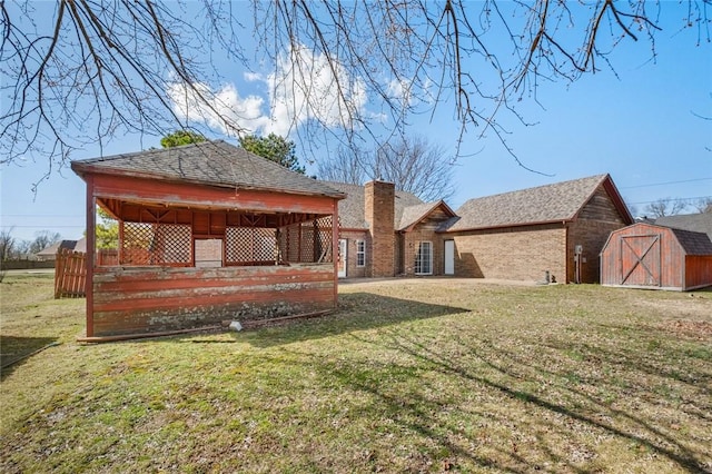 back of property featuring brick siding, a shed, a lawn, and an outdoor structure