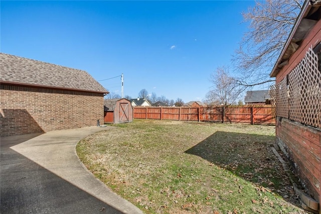 view of yard with an outbuilding, a storage unit, and a fenced backyard