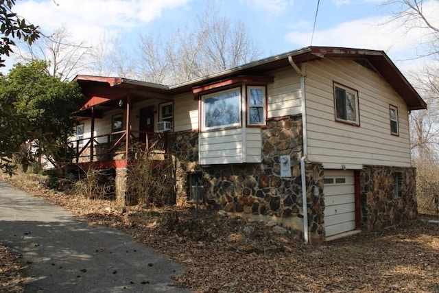 view of home's exterior with stone siding, covered porch, and an attached garage