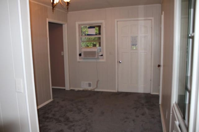 interior space with visible vents, dark carpet, cooling unit, wood walls, and a chandelier