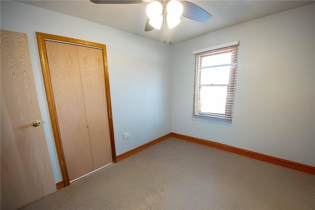 unfurnished bedroom featuring carpet flooring, a ceiling fan, baseboards, and a closet