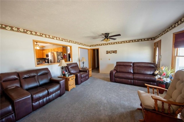 living area with carpet, a ceiling fan, and a textured ceiling