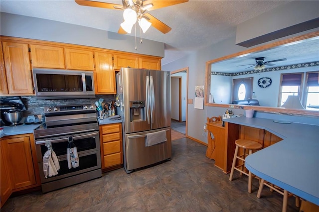 kitchen featuring ceiling fan, decorative backsplash, light countertops, stainless steel appliances, and a textured ceiling