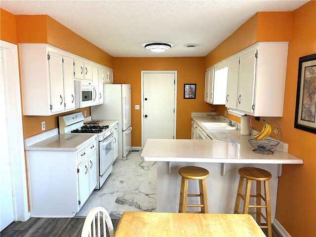 kitchen featuring white cabinetry, white appliances, light countertops, and a sink