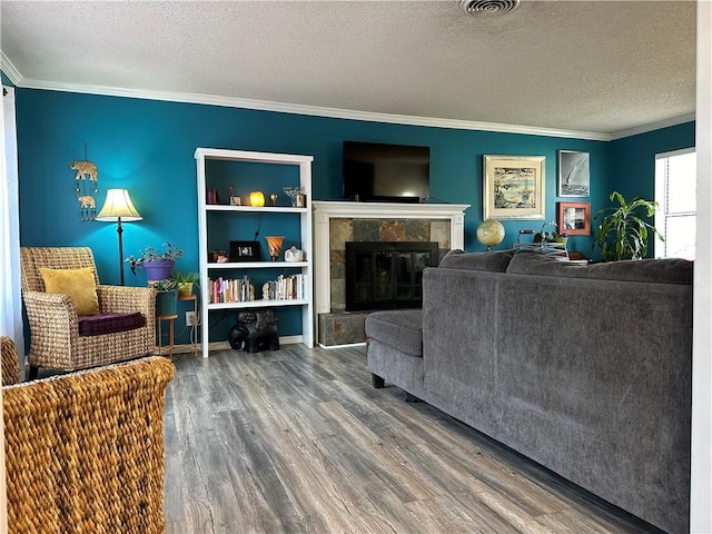 living area with ornamental molding, wood finished floors, a tile fireplace, and a textured ceiling