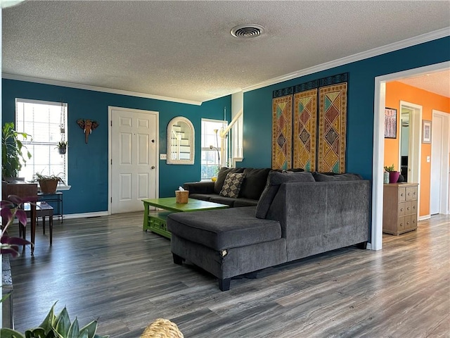 living area featuring wood finished floors, baseboards, visible vents, a textured ceiling, and crown molding