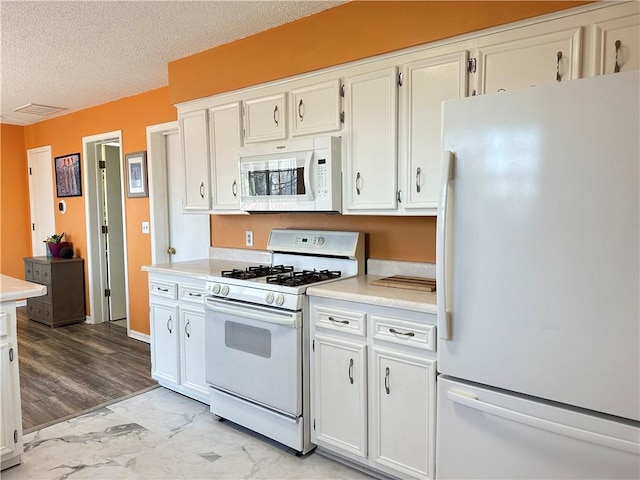 kitchen with visible vents, white appliances, a textured ceiling, and light countertops