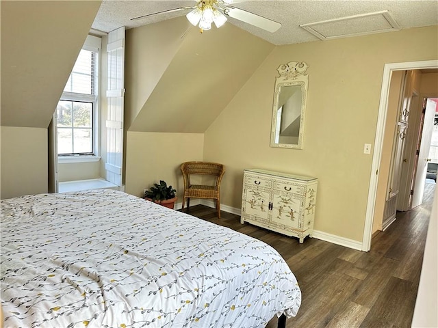 bedroom with baseboards, dark wood finished floors, attic access, lofted ceiling, and a textured ceiling