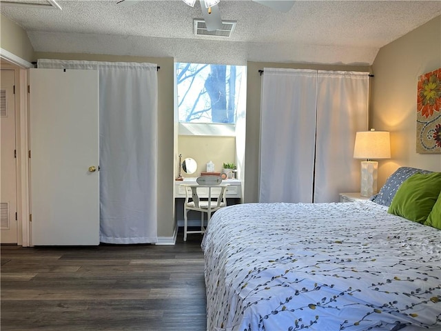 bedroom with visible vents, a textured ceiling, dark wood-style flooring, and vaulted ceiling