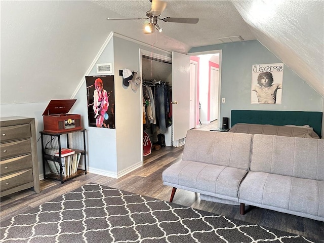 bedroom featuring visible vents, a textured ceiling, wood finished floors, a closet, and vaulted ceiling