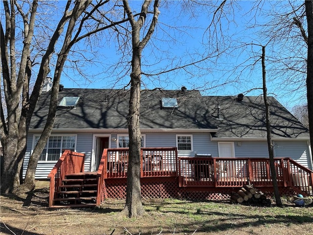 rear view of house featuring a shingled roof and a deck