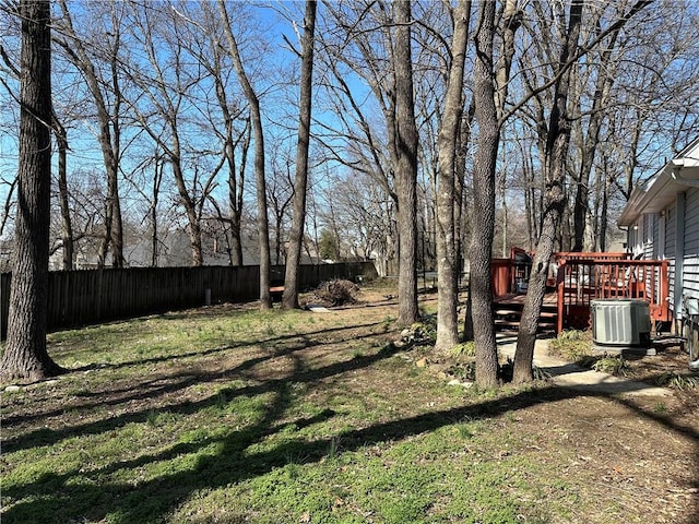 view of yard with a deck, fence, and central AC