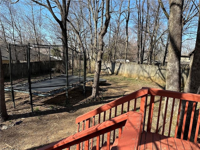 wooden terrace featuring a trampoline and a fenced backyard