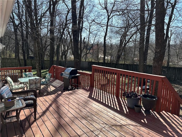 wooden deck featuring outdoor dining space, a fenced backyard, and grilling area