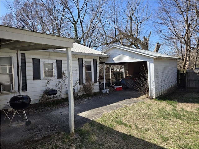 view of side of property with metal roof, a yard, driveway, and fence