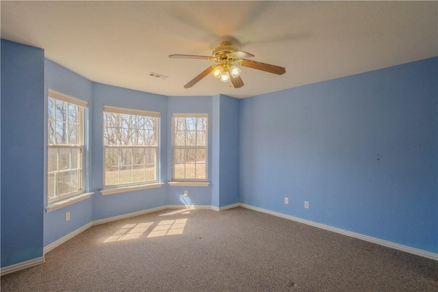 carpeted spare room featuring visible vents, ceiling fan, and baseboards