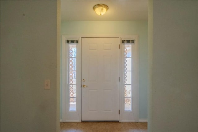 entrance foyer with a wealth of natural light, baseboards, and light tile patterned flooring