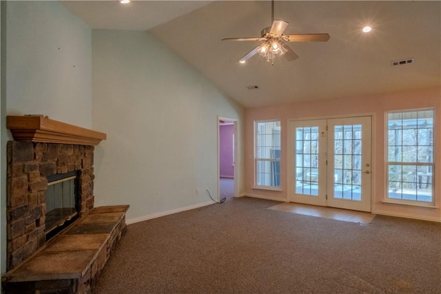 unfurnished living room with carpet, baseboards, ceiling fan, a stone fireplace, and vaulted ceiling