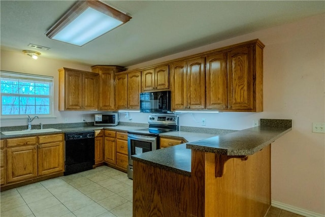 kitchen featuring visible vents, a peninsula, brown cabinetry, black appliances, and a sink