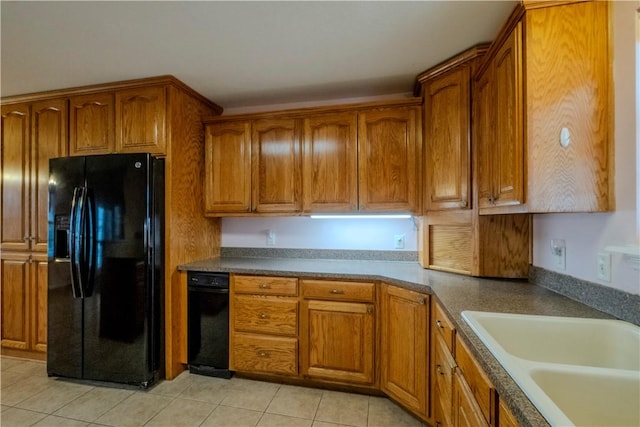 kitchen featuring a sink, brown cabinets, black fridge with ice dispenser, and light tile patterned flooring