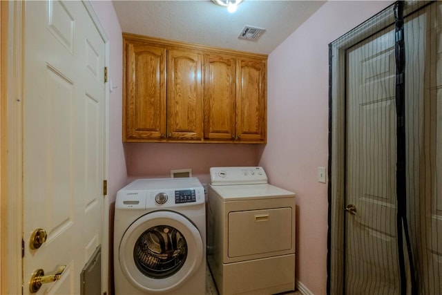 washroom with visible vents, cabinet space, and separate washer and dryer