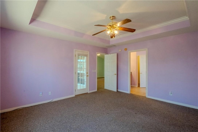 unfurnished bedroom featuring baseboards, carpet floors, a tray ceiling, ceiling fan, and crown molding