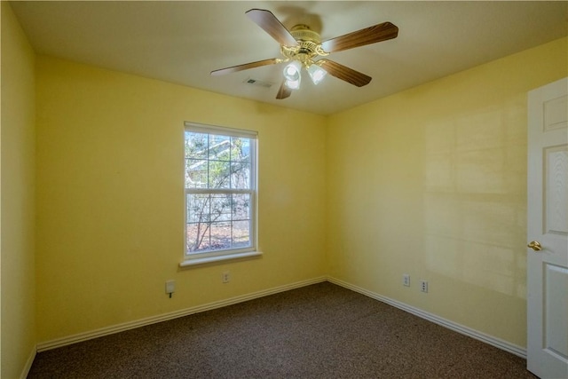 spare room with visible vents, a ceiling fan, baseboards, and dark colored carpet