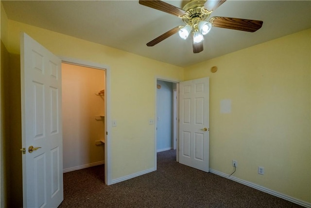 unfurnished bedroom with carpet, baseboards, a ceiling fan, a closet, and a walk in closet