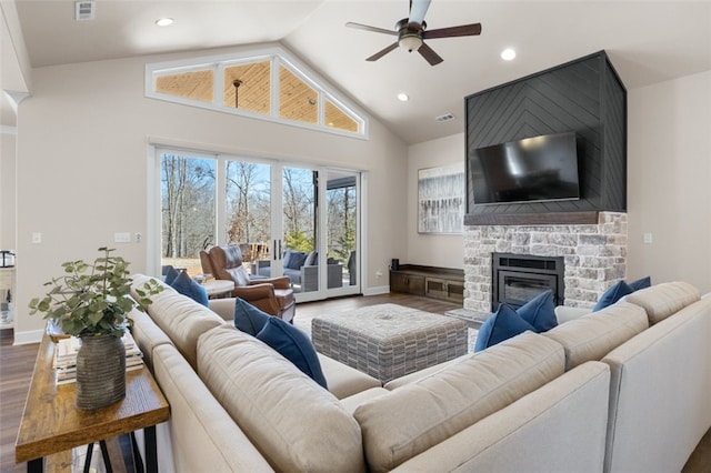 living area featuring a stone fireplace, wood finished floors, visible vents, and baseboards