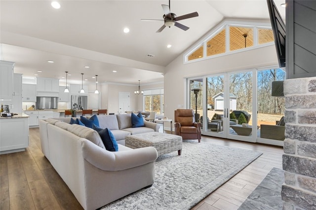 living area featuring recessed lighting, light wood-style flooring, high vaulted ceiling, and ceiling fan with notable chandelier