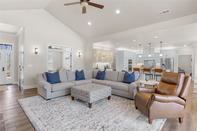 living area featuring visible vents, high vaulted ceiling, light wood-style flooring, ornamental molding, and recessed lighting